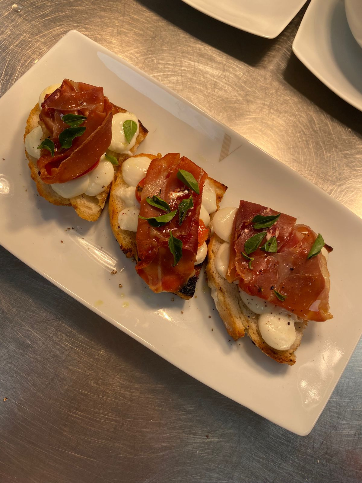 Bruschetta de muçarela de búfula, tomate assado, manjerição e parma